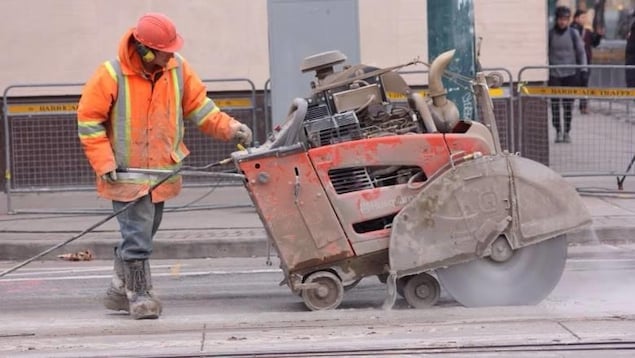 Un ouvrier procède à la réfection d'une route. Un ouvrier procède à la réfection d'une route.