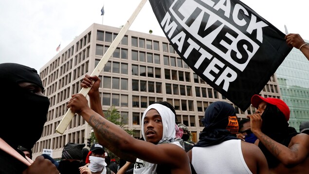 Des jeunes hommes noirs à une manifestation. L'un d'entre eux fait flotter un drapeau « Black Lives Matter », Des jeunes hommes noirs à une manifestation. L'un d'entre eux fait flotter un drapeau « Black Lives Matter »,