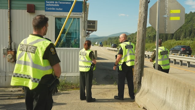 Des policiers et des contrôleurs routiers à côté de leur poste de contrôle, à l'extérieur, l'été.