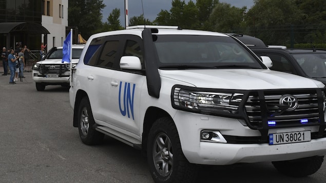 Des véhicules de l'ONU circulent sur une route.