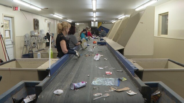 Des employés sont à l'œuvre au centre de tri de matières recyclables.