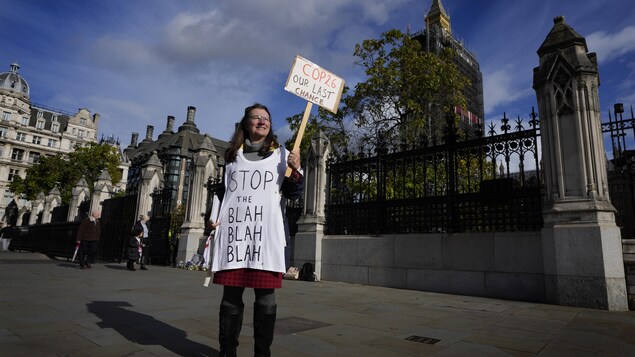 Une femme tient une pancarte devant le parlement britannique.