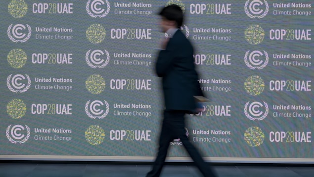 Un homme passe devant une affiche faisant la promotion de la COP28.
