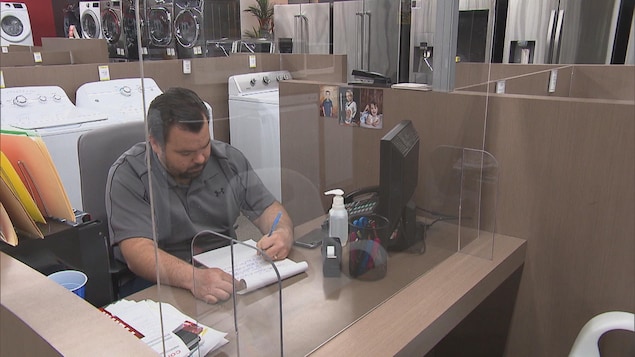Sébastien Alaire écrit assis à son bureau dans le magasin.
