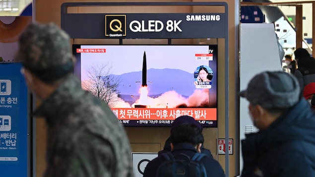 Des voyageurs regardent un écran diffusant le lancement d'un missile nord-coréen.