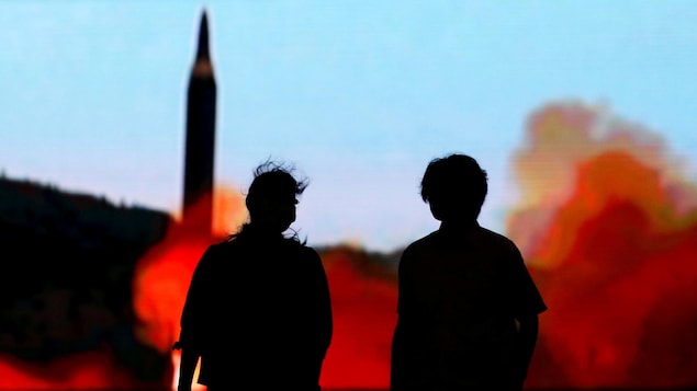 Deux personnes font face à un écran diffusant les nouvelles concernant la nouvelle menace nord-coréenne. (Tokyo, Japon)