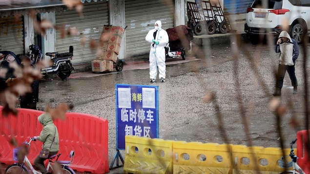 Un homme vêtu d'un habit de protection contre la contamination se tient debout dans le marché fermé.