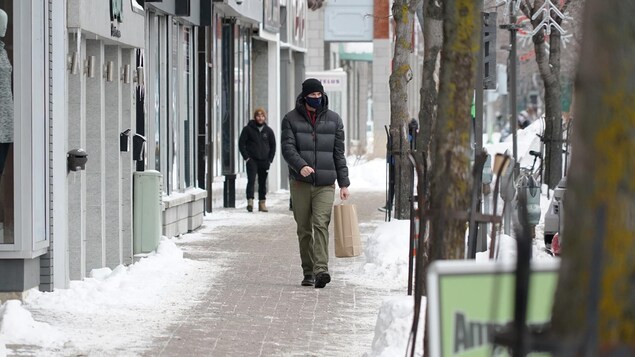 Un homme qui porte un couvre-visage déambule sur la rue Saint-Germain à Rimouski.