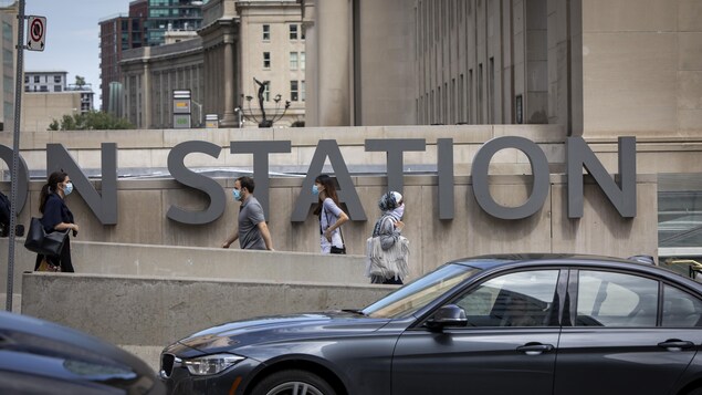 Des personnes portant un masque marche devant la gare Union de Toronto.