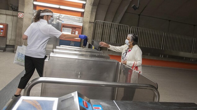 Une jeune employée de la STM tend un masque à une dame.
Photo prise au métro Langelier, à Montréal, Québec, Canada.
Le 25 Mai 2020 2020/05/25.