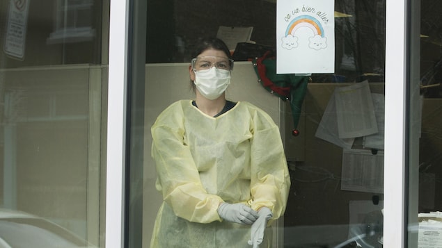 Eveline Gaillardetz est vêtue d'un habit de protection, d'un masque, de gants et de lunettes protectrices dans un local vitré.