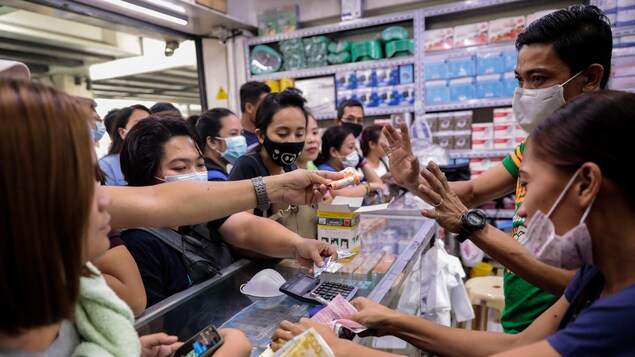 Plusieurs personnes dans un commerce, portant des masques chirurgicaux.