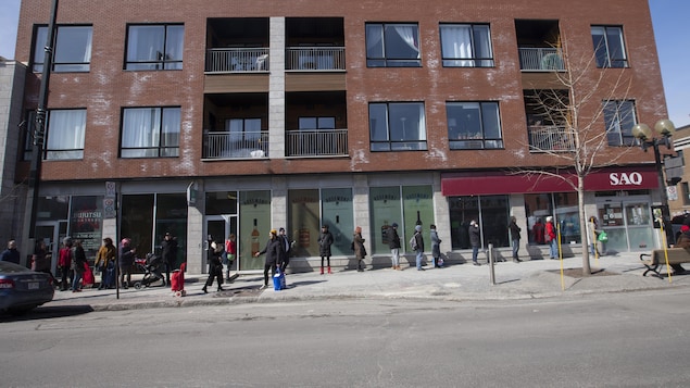 Longue file de personnes devant un magasin de la SAQ.