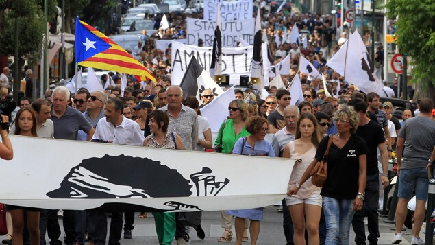 Des manifestants tiennent des pancartes qui disent « Amnistie » et « Statut de résident ». Des manifestants tiennent des pancartes qui disent « Amnistie » et « Statut de résident ».