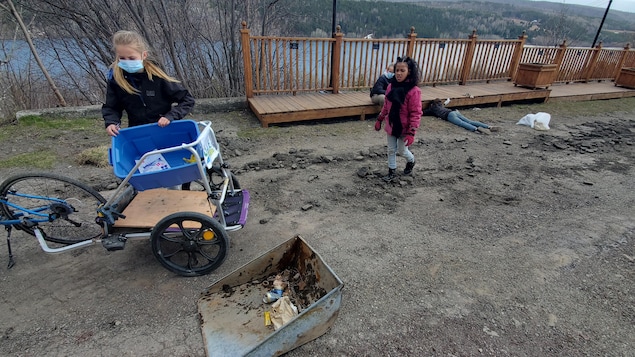 Deux jeunes filles ramassent des déchets devant un belvédère.
