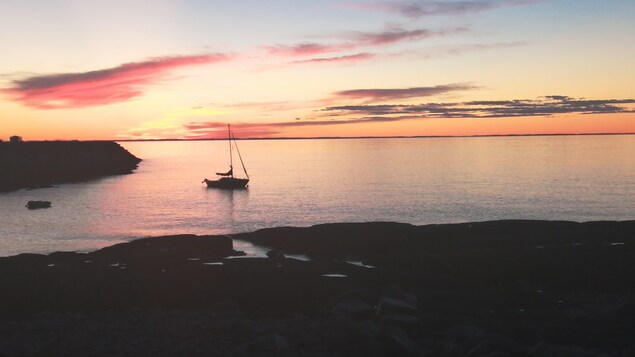 Un voilier est amarré à côté du quai de Pointe-au-Père, au crépuscule.