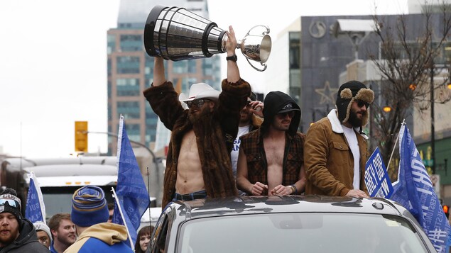 Des joueurs tiennent la coupe Grey dans leurs mains.