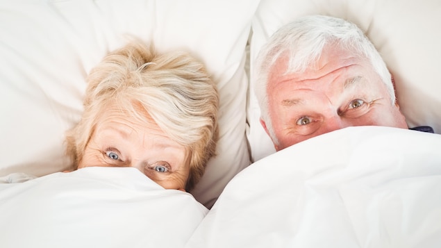 Un couple se cache sous des couvertures.