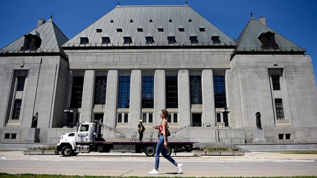 A woman walks in front of the Supreme Court of Canada building.