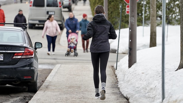 Une joggeuse circule sur un trottoir.