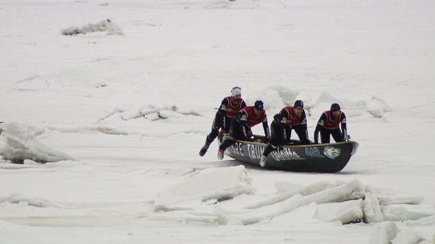 Des canotiers à glace font avance leur embarcation pendant une course.