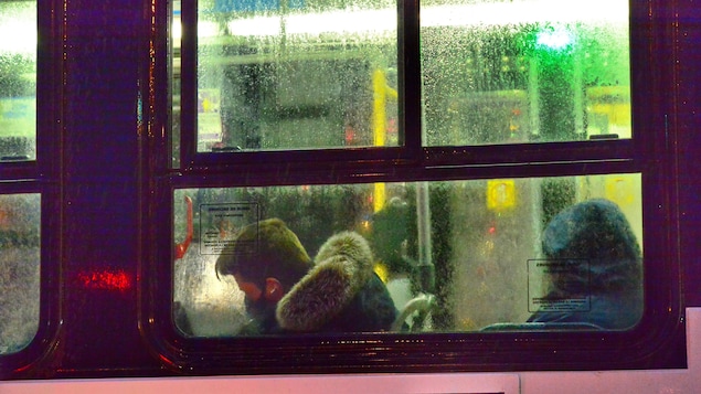 Un homme masqué assis dans un autobus.