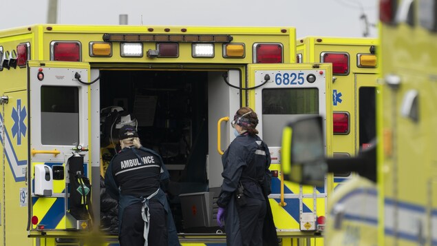 Deux ambulanciers près d'une ambulance.