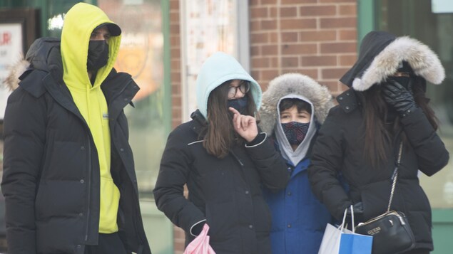 Quatre personnes sont dans la rue avec des sacs.