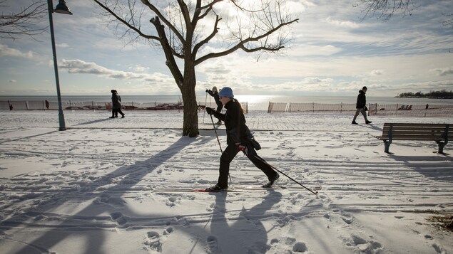 Une femme pratique le ski de fond sur la piste cyclable enneigée aux abords du lac Ontario.