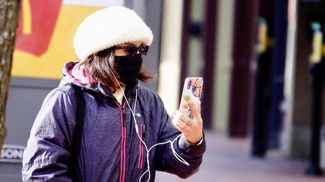 Une femme portant un masque parle au téléphone.