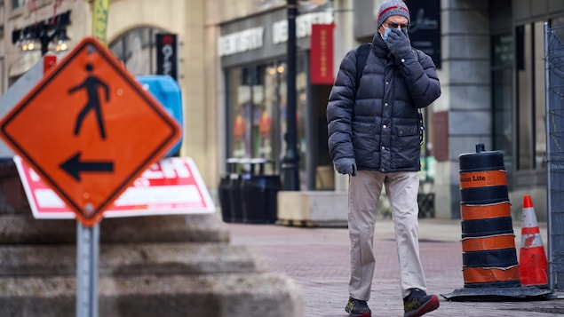 Un homme marche dans la rue avec un masque.