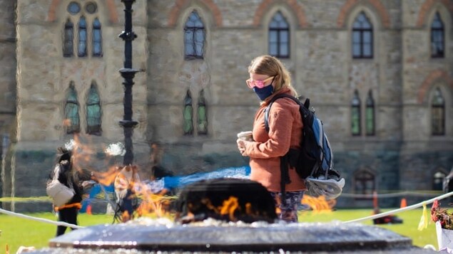 A person in sunglasses and a mask walks past the Centennial Flame in Ottawa on Sept. 30, 2021, during the COVID-19 pandemic. (Trevor Pritchard/CBC)