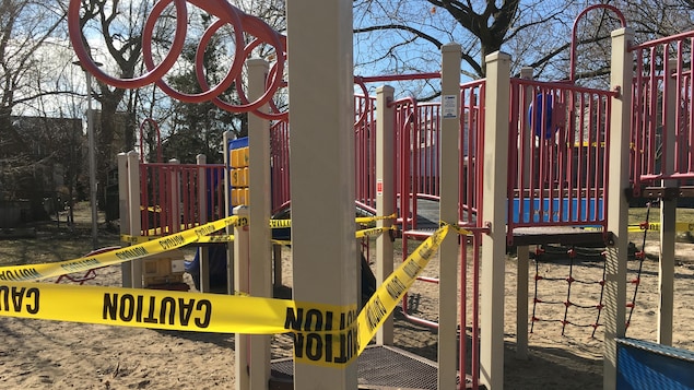 Une banderole jaune autour d'une structure de jeux dans un parc.