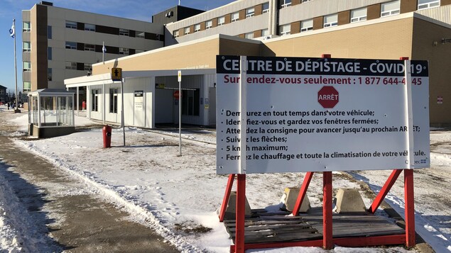 Un petit bâtiment couvert où peut pénétrer une voiture adjacent à un hôpital.