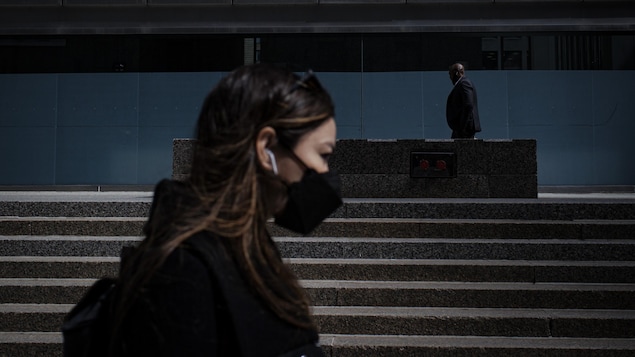 Une jeune femme portant un masque marche au centre-ville de Toronto.