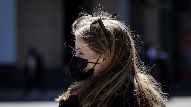 Une femme portant un masque dans la rue à Toronto.