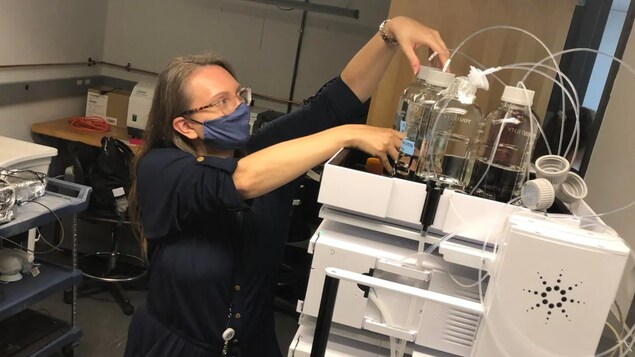 Une femme masquée ajuste des échantillons liquides.