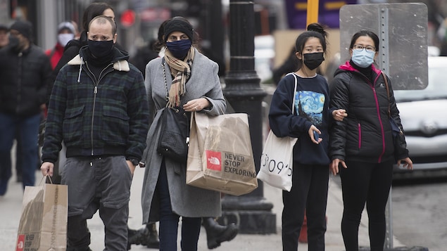 Des gens portant des masques marchent au centre-ville.