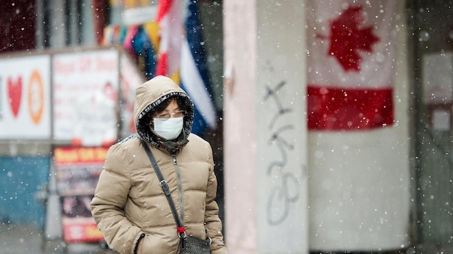 Une femme sur le trottoir, sous la neige