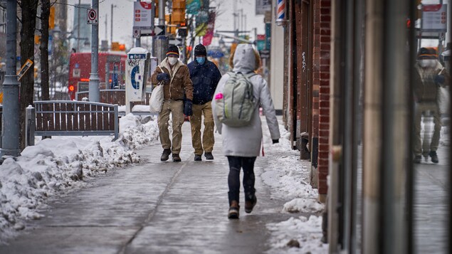 Des gens marchent sur un trottoir en hiver.                     