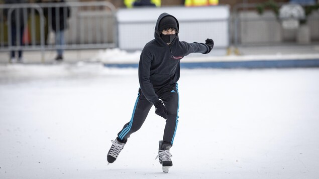 Un garçon qui porte un masque patine à l'extérieur à Toronto.