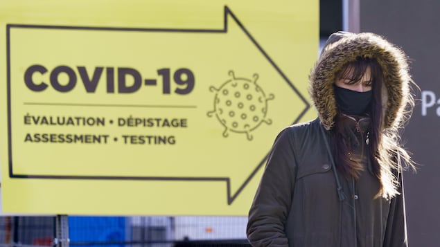 Une femme passe devant une clinique de test COVID-19 à Montréal.