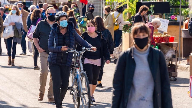 Des personnes marchent dehors avec un masque.