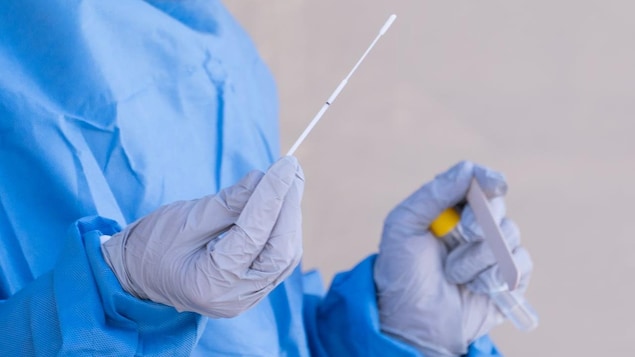 A person holding a COVID-19 swab test.