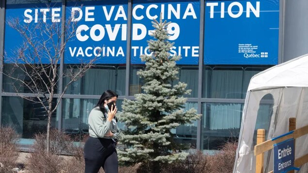 A woman walks past a COVID-19 vaccination clinic in Montreal in this photo taken April 6. New research published Monday in the Canadian Medical Association Journal credits Canada's strong COVID-19 performance to restrictive and persistent public health measures, as well as a successful vaccination campaign. (Ryan Remiorz/The Canadian Press)