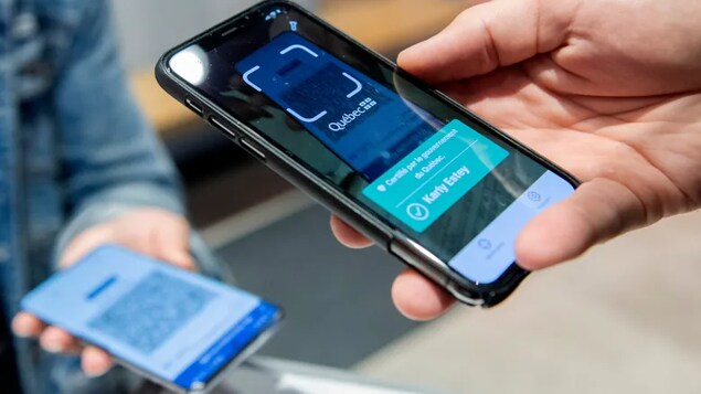 A woman has her COVID-19 vaccine passport scanned by the manager of a Montreal gym on Sept. 1, as the Quebec government’s passport system comes into effect.