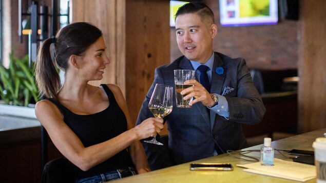 Un homme et une femme trinquent avec des verres d'alcool.