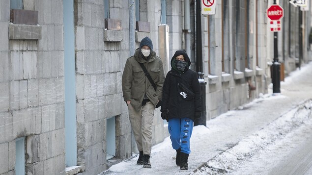 Deux personnes masquées marchent dans une rue de Montréal.