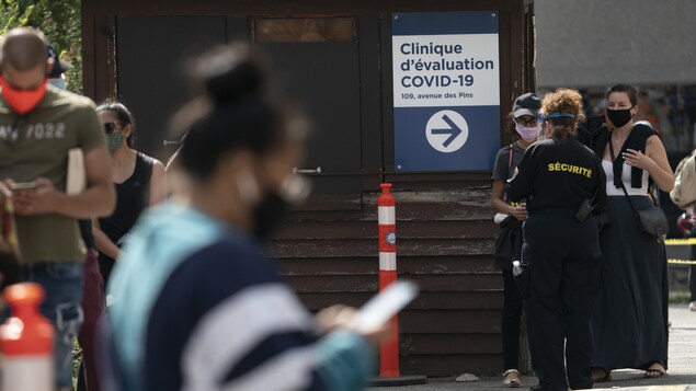 Des gens portant un masque font la file pour passer un test de dépistage de la COVID-19.