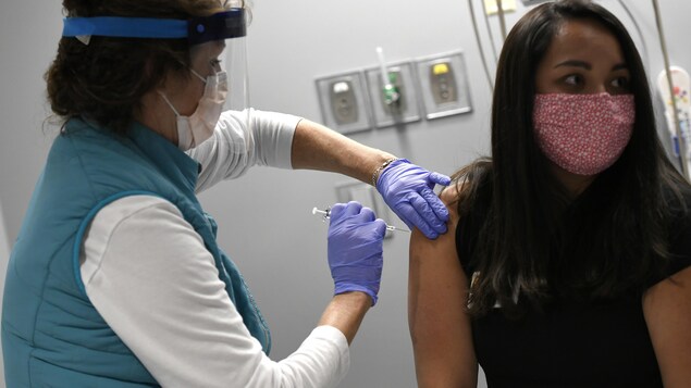 Une infirmière donne un vaccin à une femme.
